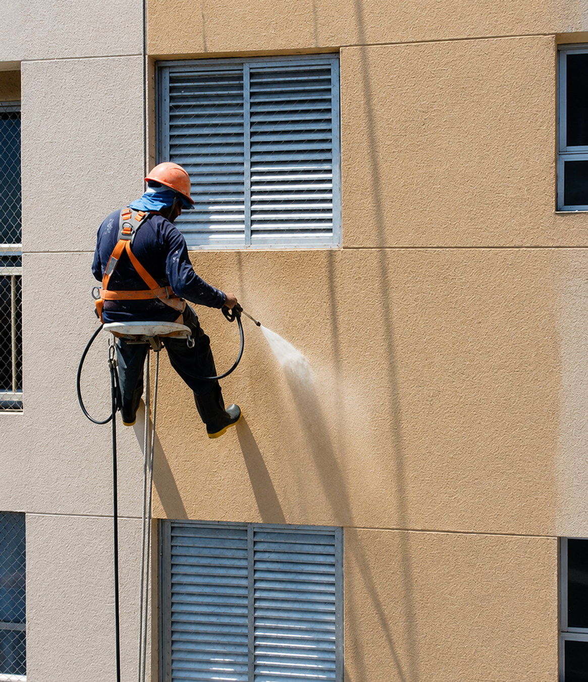Profissional realizando hidrojateamento de fachada com acesso por cordas